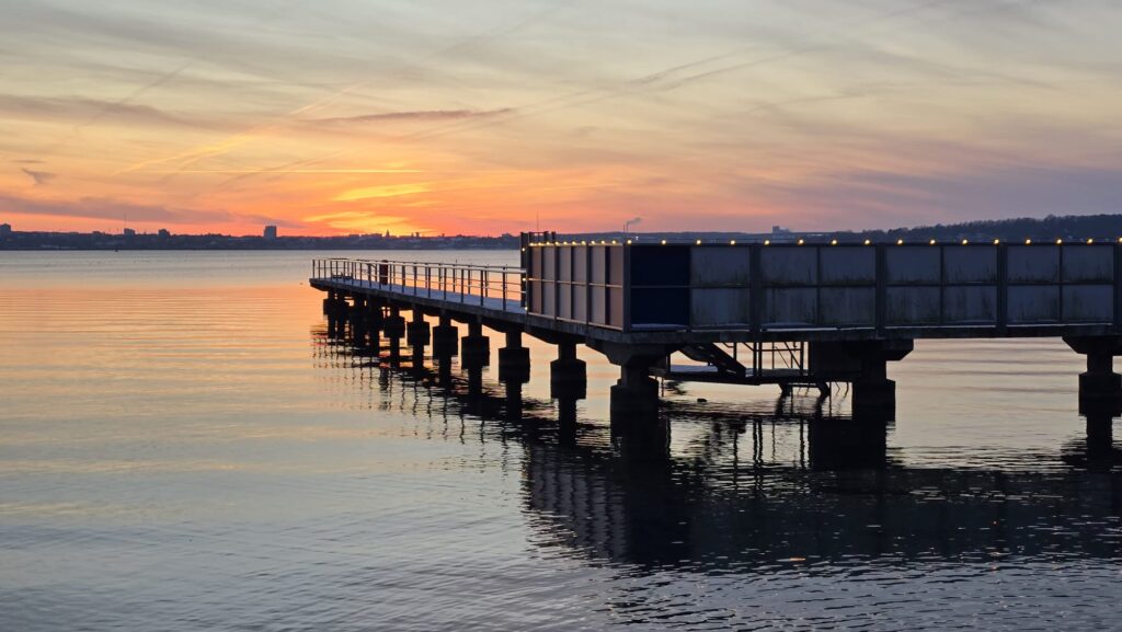 Steg der Seebadeanstalt mit orangem Sonnenuntergang